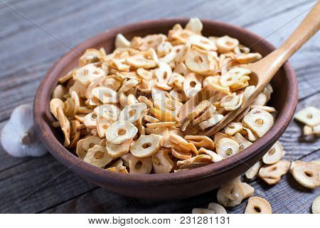 Bowl With Dried Garlic Flakes On Wooden Table