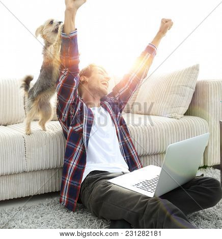 happy guy exults with his dog sitting near the sofa in the livin