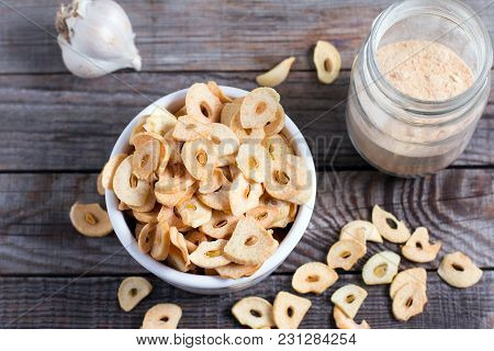 Dried Garlic Flakes Or Garlic Chips And Raw Garlic Bulb On Wooden Background