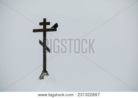 Telephoto View Of A Bird Perched On A Christian Cross Atop And An Old Church Spire
