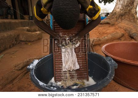 Young Boy Washing Dirty Clothes In A Washing Board And Tub In The Town Of Nhacra In Guinea Bissau, W