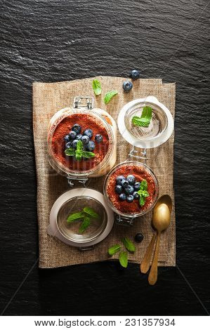 Tiramisu, Traditional Italian Dessert. With Savoyardi Cookies And Coffee. On Black Stone Background.