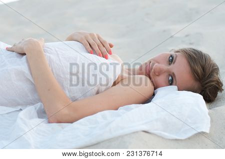 The Woman Or Girl Is Lying On The Sand And Smiling Is Looking Into The Camera Lens