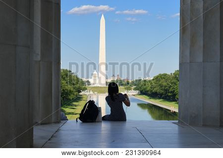A tourist silhouette at the steps of Lincoln Memorial with Washington Monument and Capitol background - Washington DC USA