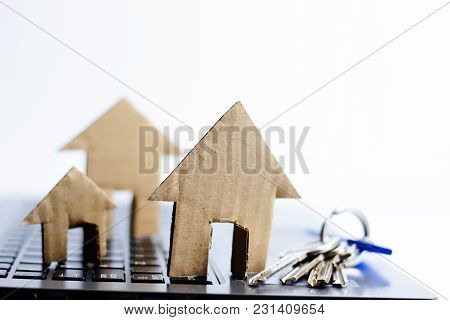 Cardboard Model House And Key On Notebook Keyboard Suggesting Online Research For A New Home