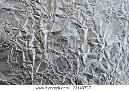 Thin Wrinkled Sheet Of Crushed Tin Aluminum Silver Foil Background With Shiny Crumpled Surface For T