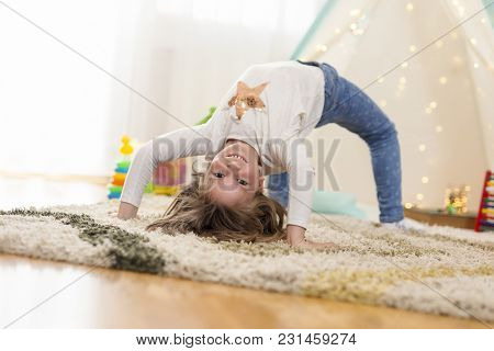 Cheerful Little Girl Doing Backbend, Playing In Her Playroom And Having Fun