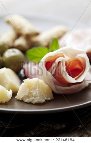 tallerken med oliven, parmesan, brød-sticks, ost og prosciutto, land vin i baggrunden