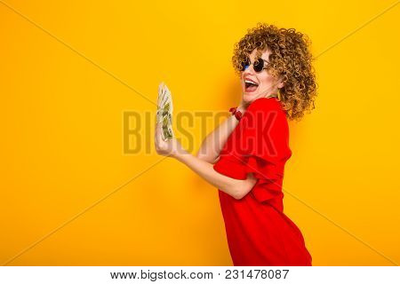 Portrait Of A White Happy Woman With Afrro Hairstyle In Red Dress And Sunglasses Holding Fan Of Euro