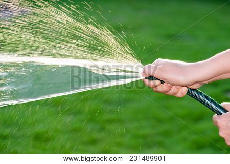 Woman Hand Holding Rubber Water Hose And Using Finger Close End Of Rubber Water Hose To Make  Water 