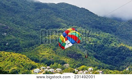 Colorful Parasailing Screen In Front Of The Green Mountains On The Coast Of Seychelles