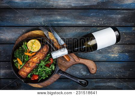 Grilled Salmon Fillet In A Frying Pan, Vegetables, Arugula With A Lemon. Served With Bottle And Glas