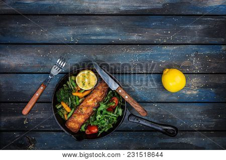 Grilled Salmon Fillet In A Frying Pan, Vegetables, Arugula With A Lemon. On The Cutting Board And Wo