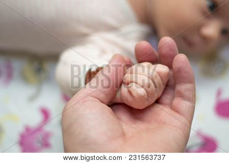 Dad Is Holding The Hand Of His Small Newborn Baby