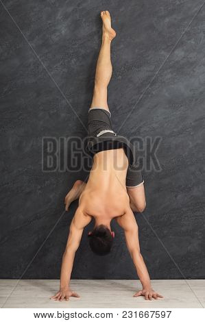 Young Flexible Man Practicing Yoga, Making Corner Stretching Exercise At Wall In Gym, Copy Space
