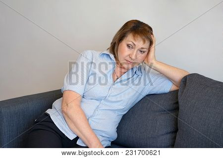 A Lonely Elderly Woman Is Sitting On The Sofa At Home. She Is Depressed And Separated From Problems 