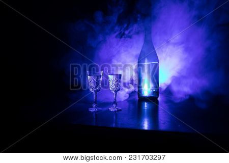 Two Glasses Of Vodka With Bottle On Dark Foggy Club Style Background With Glowing Lights (laser, Sto