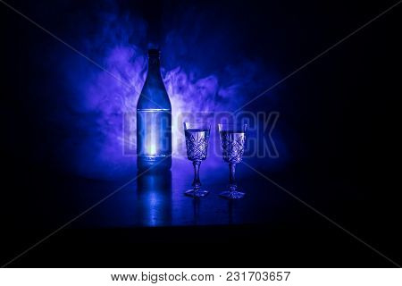 Two Glasses Of Vodka With Bottle On Dark Foggy Club Style Background With Glowing Lights (laser, Sto