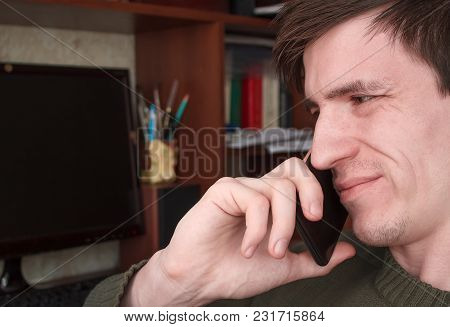 Young Guy Talking On A Black Smartphone With A Smile