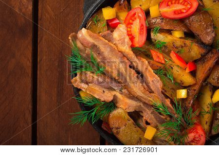 Fried Potatoes With Bacon And Fresh Tomatoes In The Frying Pan. Wooden Rustic Background. Top View.