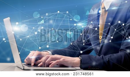Businessman typing on laptop with linked reports charts grapghs around