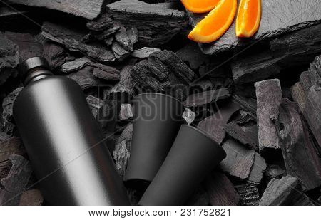 Original Black Matte Bottle Of Vodka Or Tequila And Shot Glass .slices Of Oranges.on Charcoal Backgr