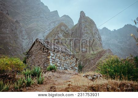Ruined Local Storehouse Nestled Into Incredible Scenery With Steep Mountain Rocks And Vertical Peaks