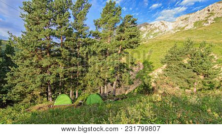 Two Tourist Tents Stand Near Trees In The Mountains At Dawn. Morning, Summer. Russia, Adygea, Lago-n