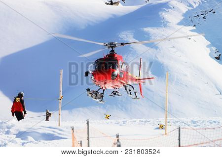 Maennlichen, Switzerland - December 31, 2013: Red Helicopter Landing At Swiss Alpine Mountain Mannli