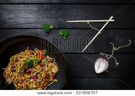 Udon Stir Fry Noodles With Meat Or Chicken And Vegetables In Wok Pan On Black Wooden Background. Wit