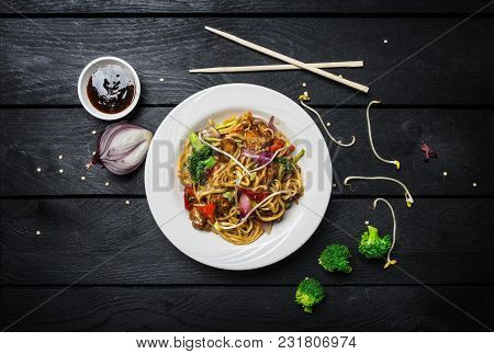 Udon Stir Fry Noodles With Meat Or Chicken And Vegetables In A White Plate On Black Wooden Backgroun