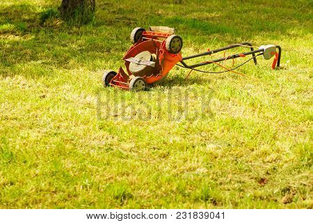 Gardening. Broken Old Lawnmower In Backyard Grass.