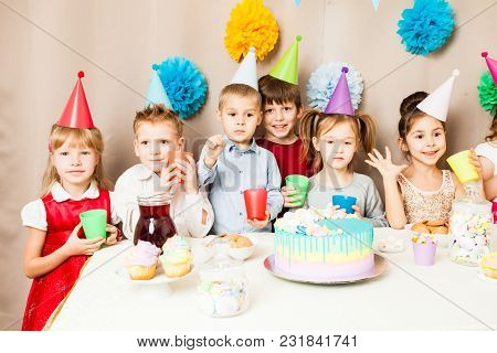 Little Kids Celebrating Birthday. Many Children Near The Table, Friends Are Exciting In The Hours Of