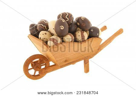 Wheel barrow full with chocolate easter eggs isolated over white background