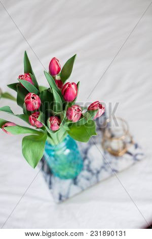 Home Interior. Bedroom. A Bouquet Of Tulips In A Glass Vase, A Candle, A Tray, A Box With A Gift Sta