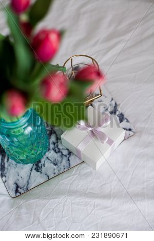 Home Interior. Bedroom. A Bouquet Of Tulips In A Glass Vase, A Candle, A Tray, A Box With A Gift Sta