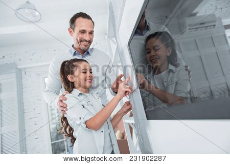 This Is Our Smart Home. Positive Joyful Cute Girl Smiling And Pressing The Button While Using The Sm