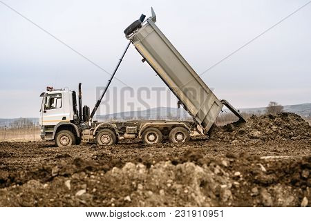 Industrial Dumper Truck Un Loading Gravel And Earth At Highway Construction Site
