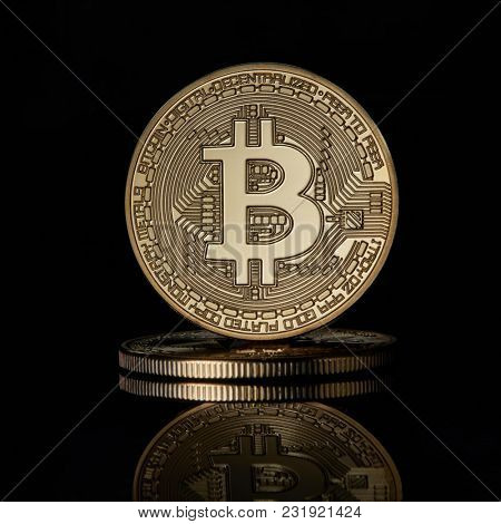Stacked golden bitcoins coins for BTC cryptocurrency on a black reflective surface background
