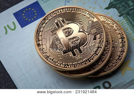 Three gold coins bitcoin stack on paper euro bill
