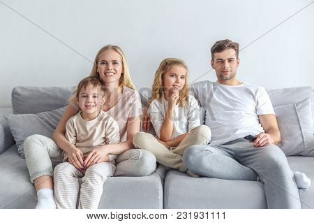 Interested Young Family Watching Movie On Couch At Home