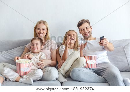Young Happy Family Watching Movie On Couch At Home