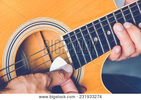 Hand Of Man Holding White Plectrum Playing Guitar