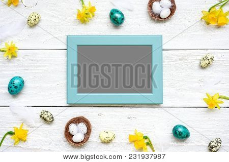 Blank Photo Card In Frame Made Of Quail Eggs, Spring Flowers And Feathers On White Wooden Background