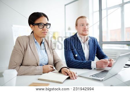 Portrait of two business peoplle sitting at meeting at office