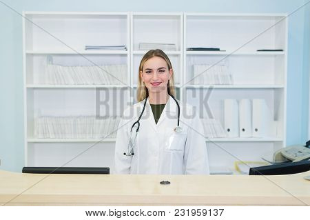 Smiling Female Doctor With Stethoscope At The Reception.