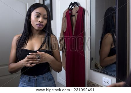 Pretty Black Female Getting Ready In Front Of A Bathroom Mirror Putting On A Ring And Jewelry.  She 