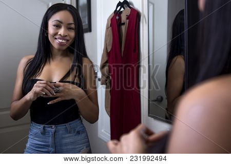 Pretty Black Female Getting Ready In Front Of A Bathroom Mirror Putting On A Ring And Jewelry.  She 