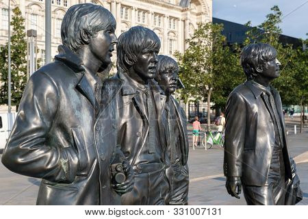 LIVERPOOL,UK - AUGUST 5,2019 : Iconic bronze statues of the four Beatles in front of the Mersey waterfront in Liverpool