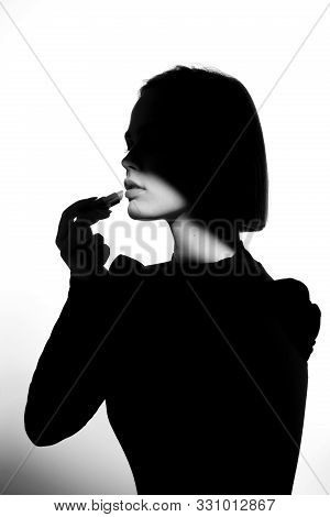 Fashion Advertising Portrait Of A Young Beautiful Girl Using Lipstick. Black And White Silhouette Wi